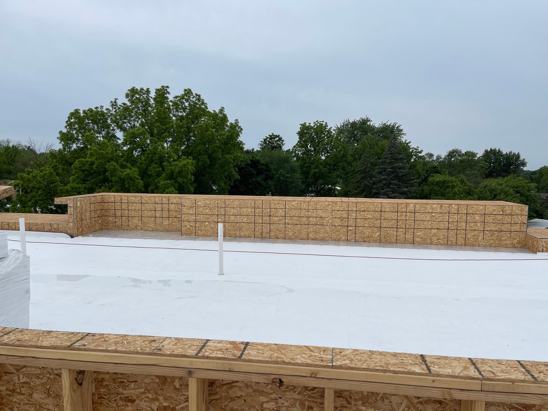 A white roof is being installed on a building under construction.