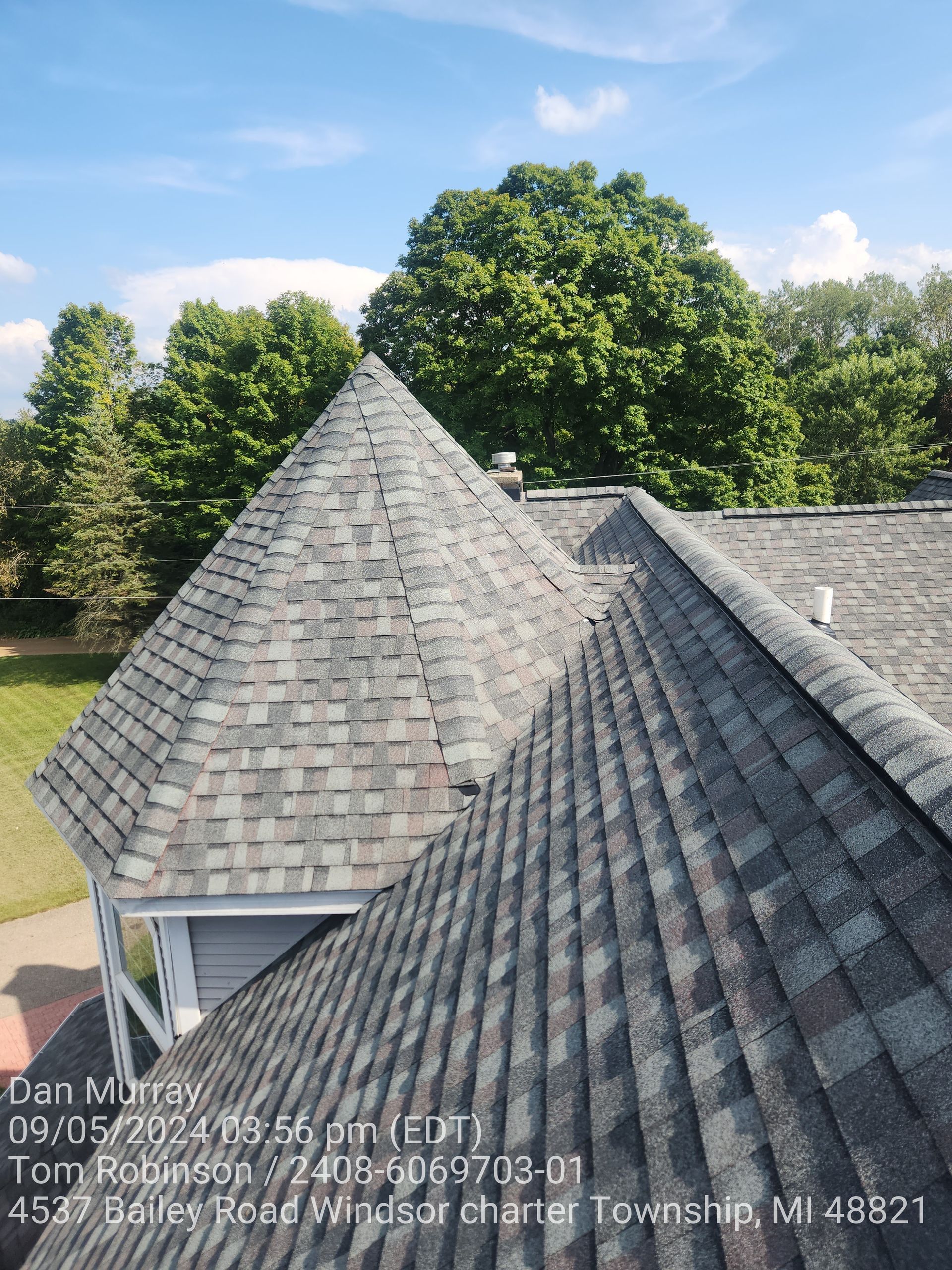 An aerial view of a roof with a tree in the background.