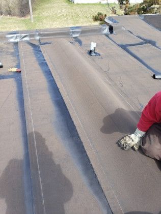 A person is working on a roof with a shovel.