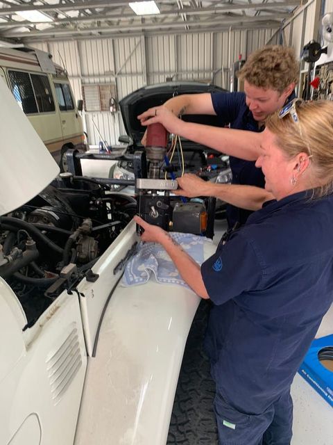 A Man and a Woman Are Working on a Car in a Garage — Cool Cats Auto Air in Urangan, QLD