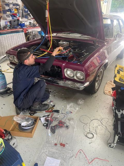 A Man is Working on a Purple Car in a Garage — Cool Cats Auto Air in Urangan, QLD