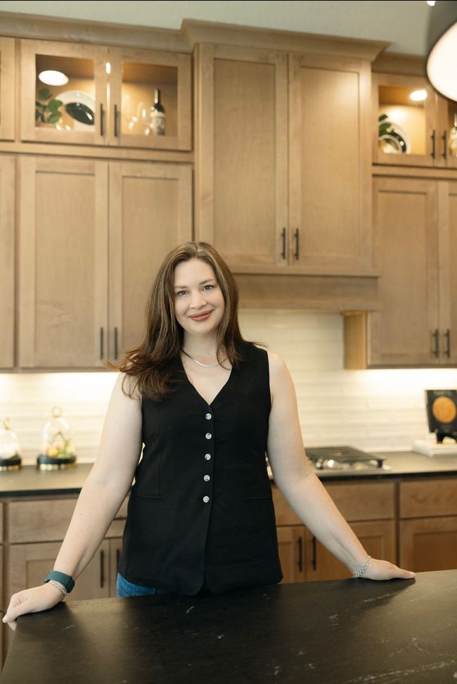 Woman in a black top standing at a kitchen island in a modern wood-toned kitchen