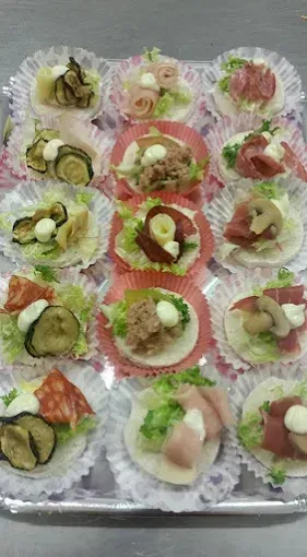 Vassoio di antipasti, ognuno su un foglio di carta decorativo, con vari condimenti come verdure, carne e salse.