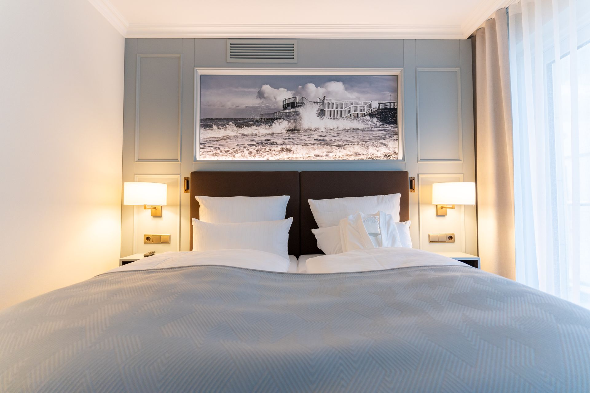 Ein Hotelzimmer mit einem großen Bett und einem Bild an der Wand darüber.