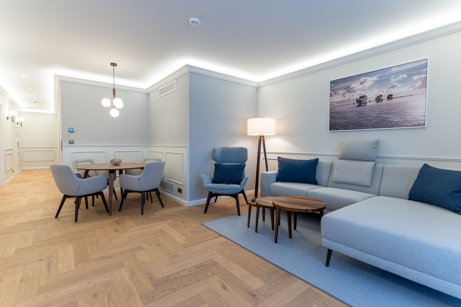 Ein Wohnzimmer mit einem Sofa, Stühlen, einem Tisch und einem Bild an der Wand.