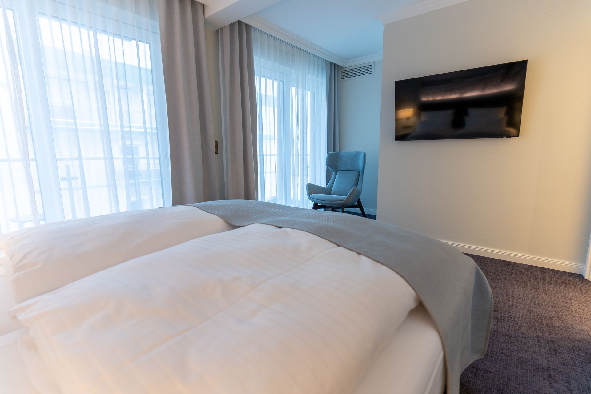 Ein Hotelzimmer mit Bett, Sessel und Fernseher.