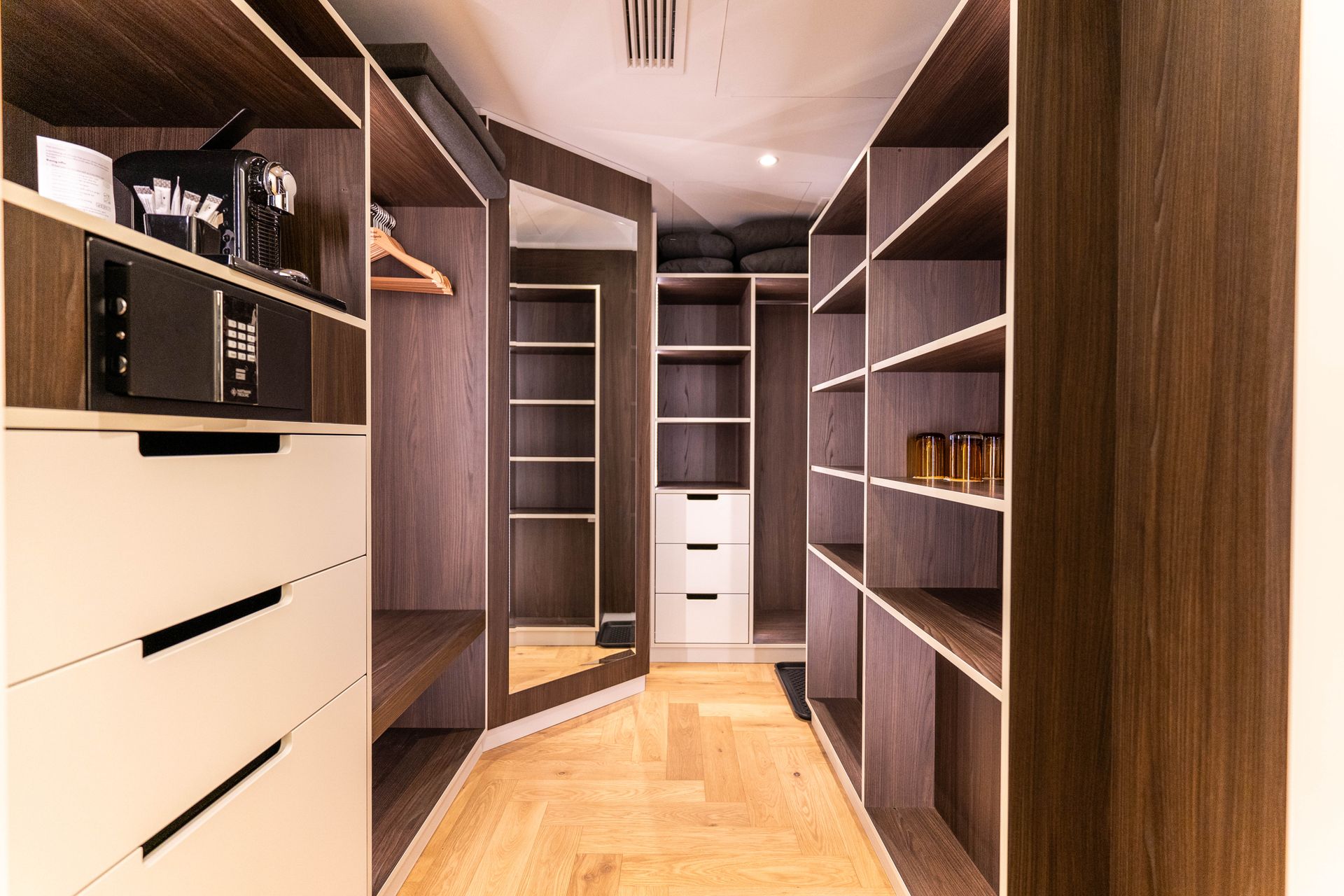 Ein begehbarer Kleiderschrank mit vielen Regalen und Schubladen und einem Spiegel.