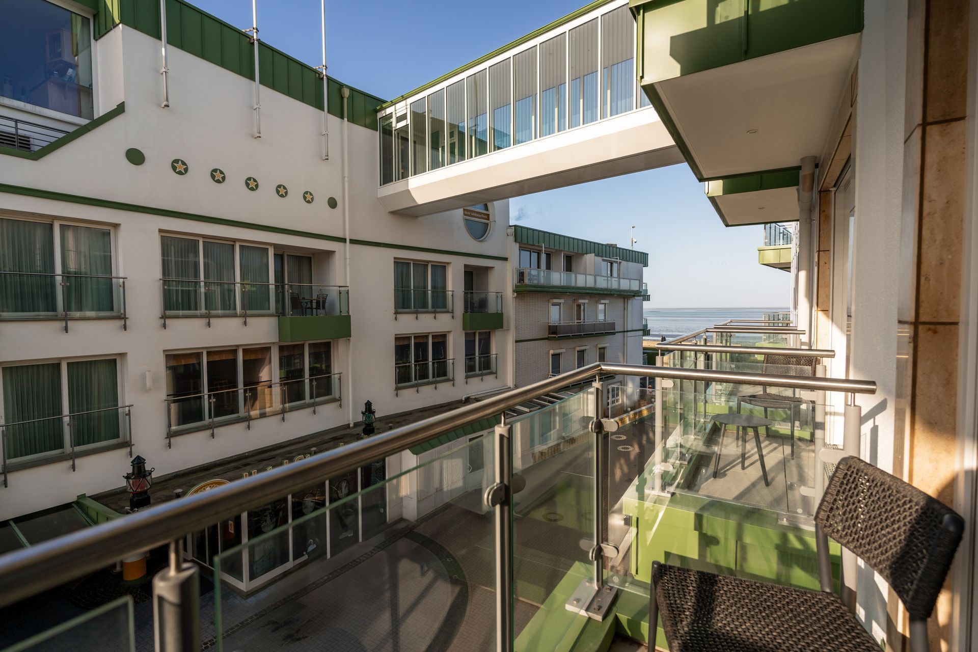 Ein Balkon mit einem Stuhl und Blick auf ein Gebäude und das Meer.