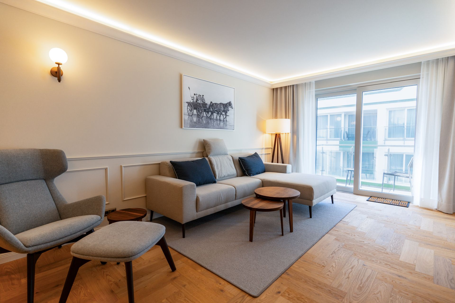 Ein Wohnzimmer mit Sofa, Sessel, Tisch und Teppich.