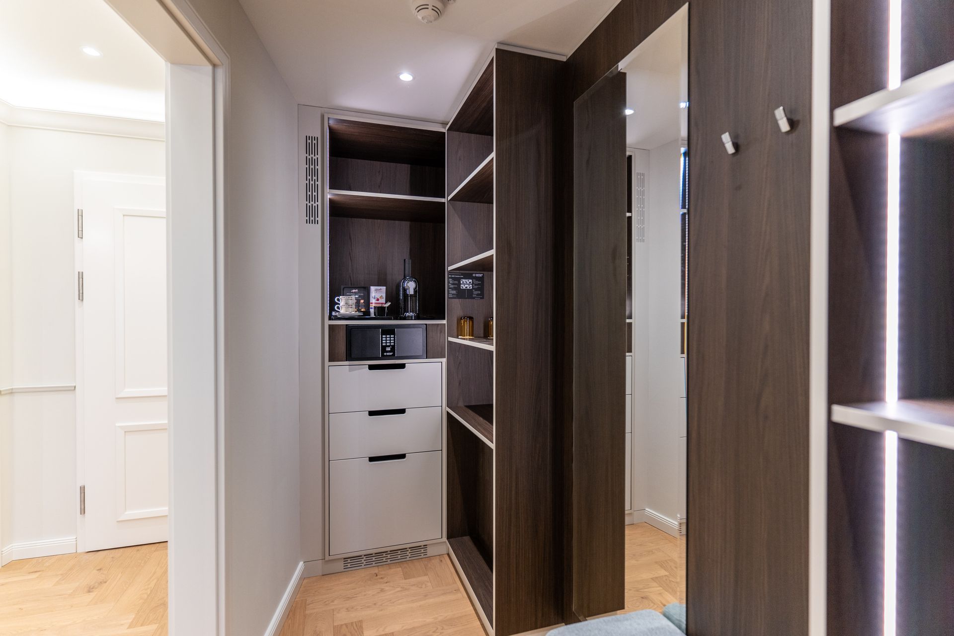 Ein begehbarer Kleiderschrank mit vielen Regalen und Schubladen und einem Spiegel.