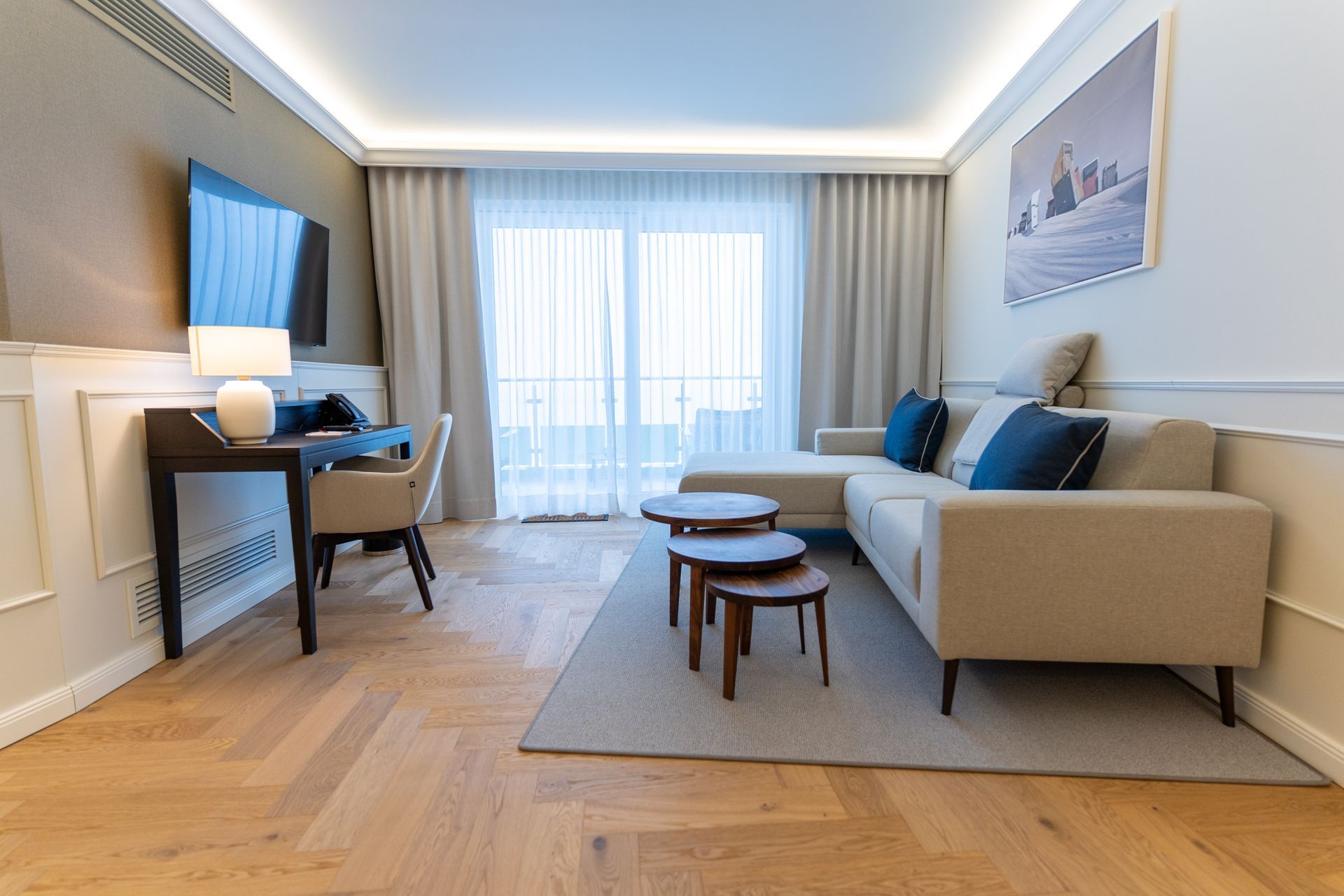 Ein Wohnzimmer mit Couch, Tisch, Schreibtisch und Fernseher.