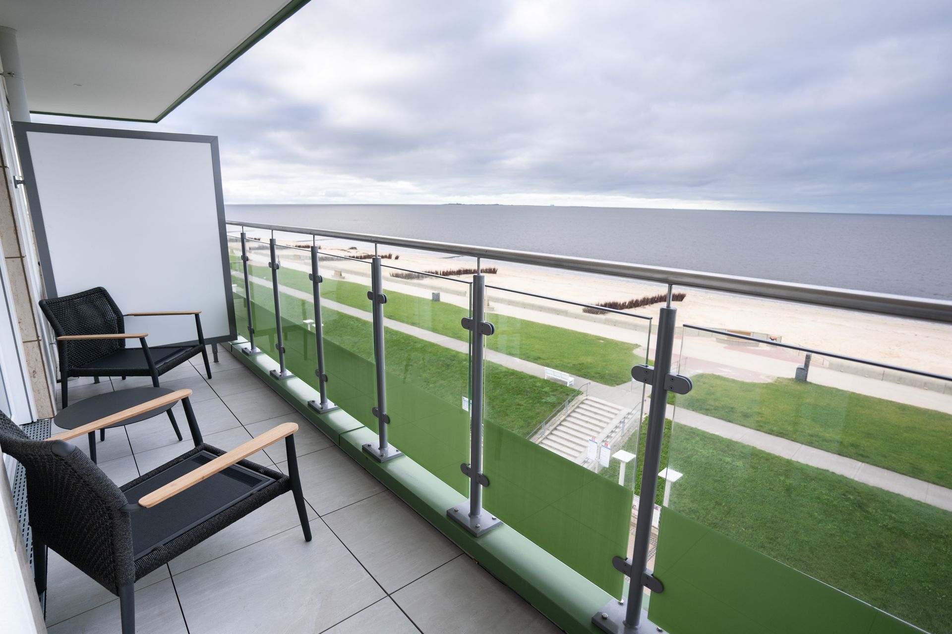 Ein Balkon mit zwei Stühlen und einem Tisch mit Blick auf das Meer.