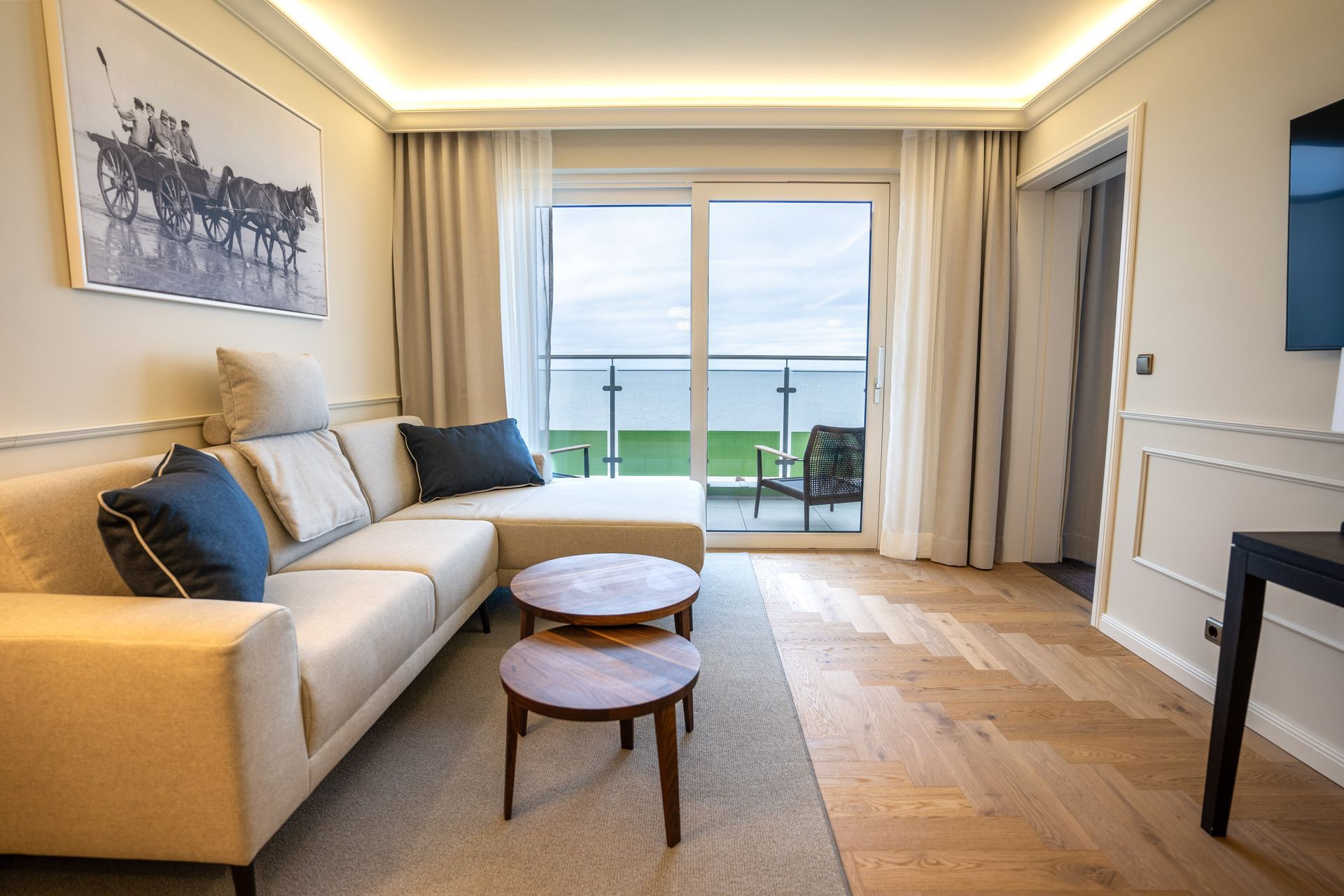 Ein Wohnzimmer mit einer Couch, zwei Tischen und einem Balkon.