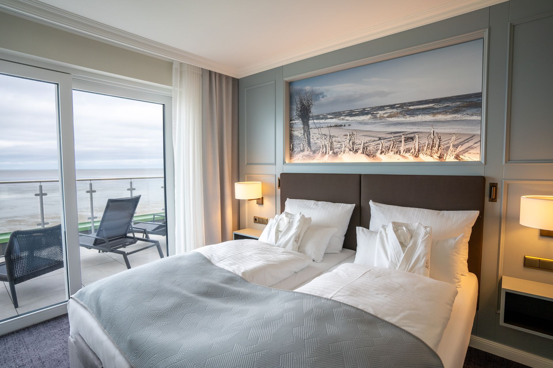 Ein Hotelzimmer mit einem großen Bett und einem Balkon mit Blick auf den Ozean.