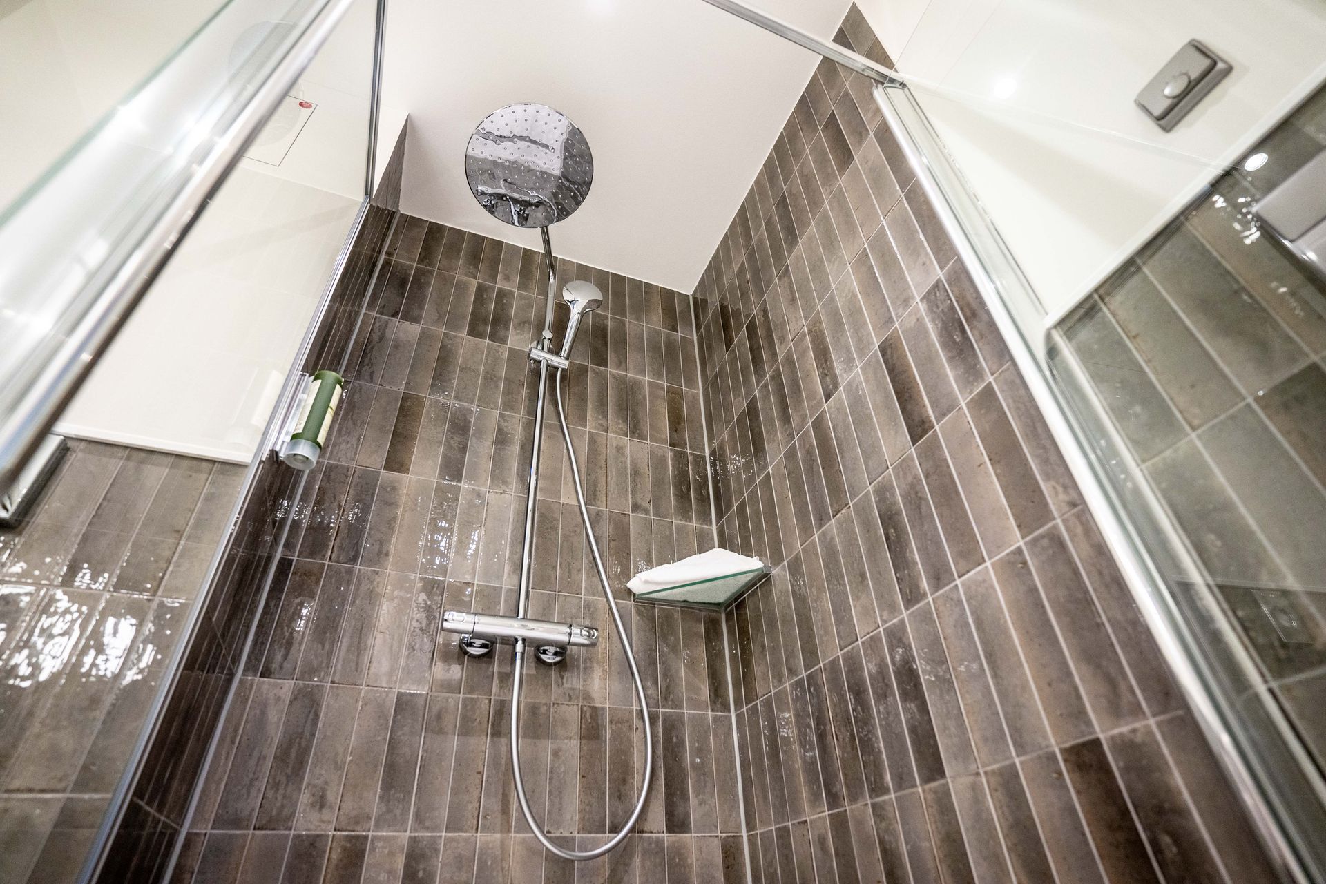 Eine Dusche mit Duschkopf und Glastür in einem Badezimmer.