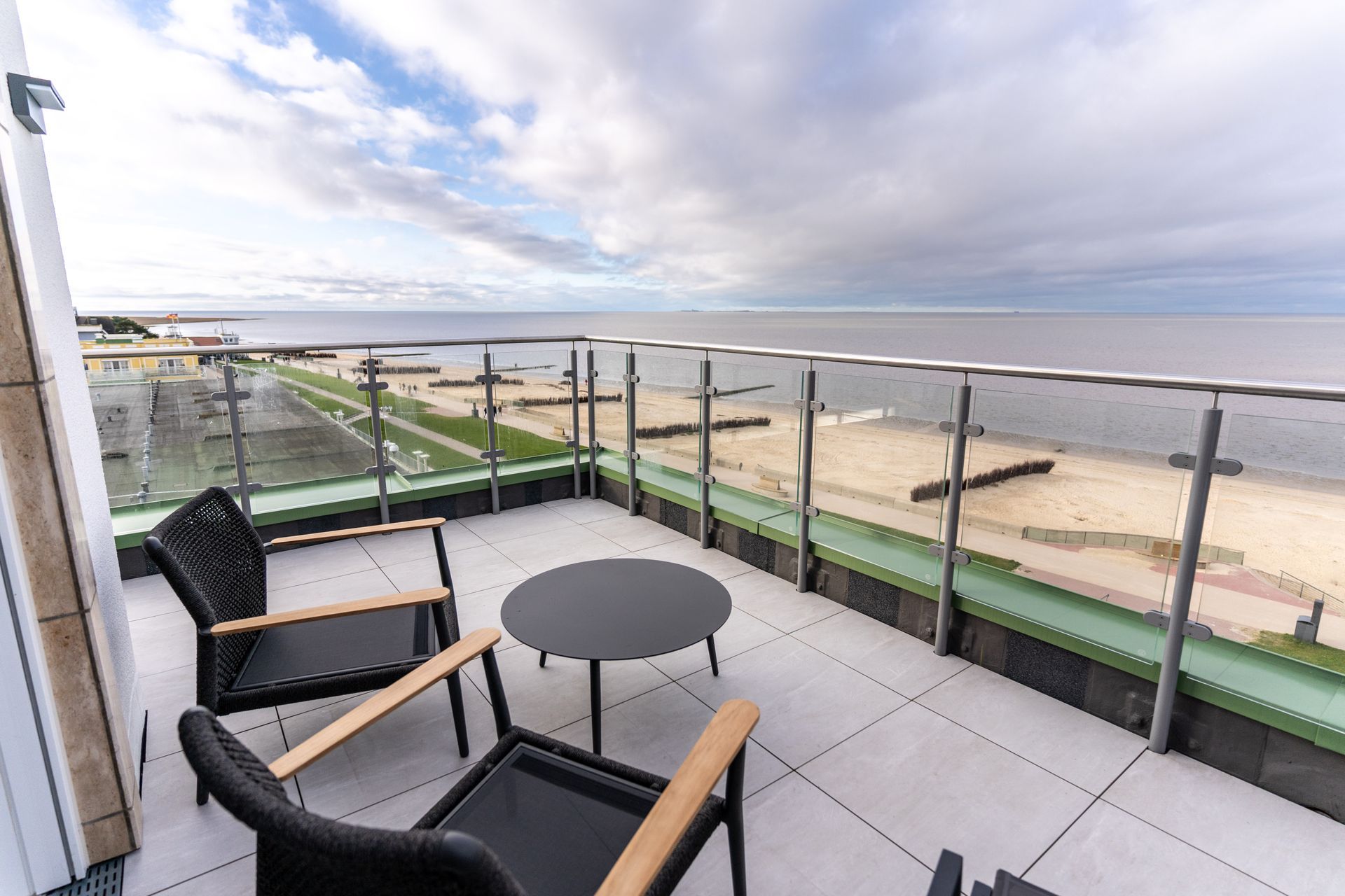 Ein Balkon mit Stühlen und einem Tisch mit Blick auf das Meer.