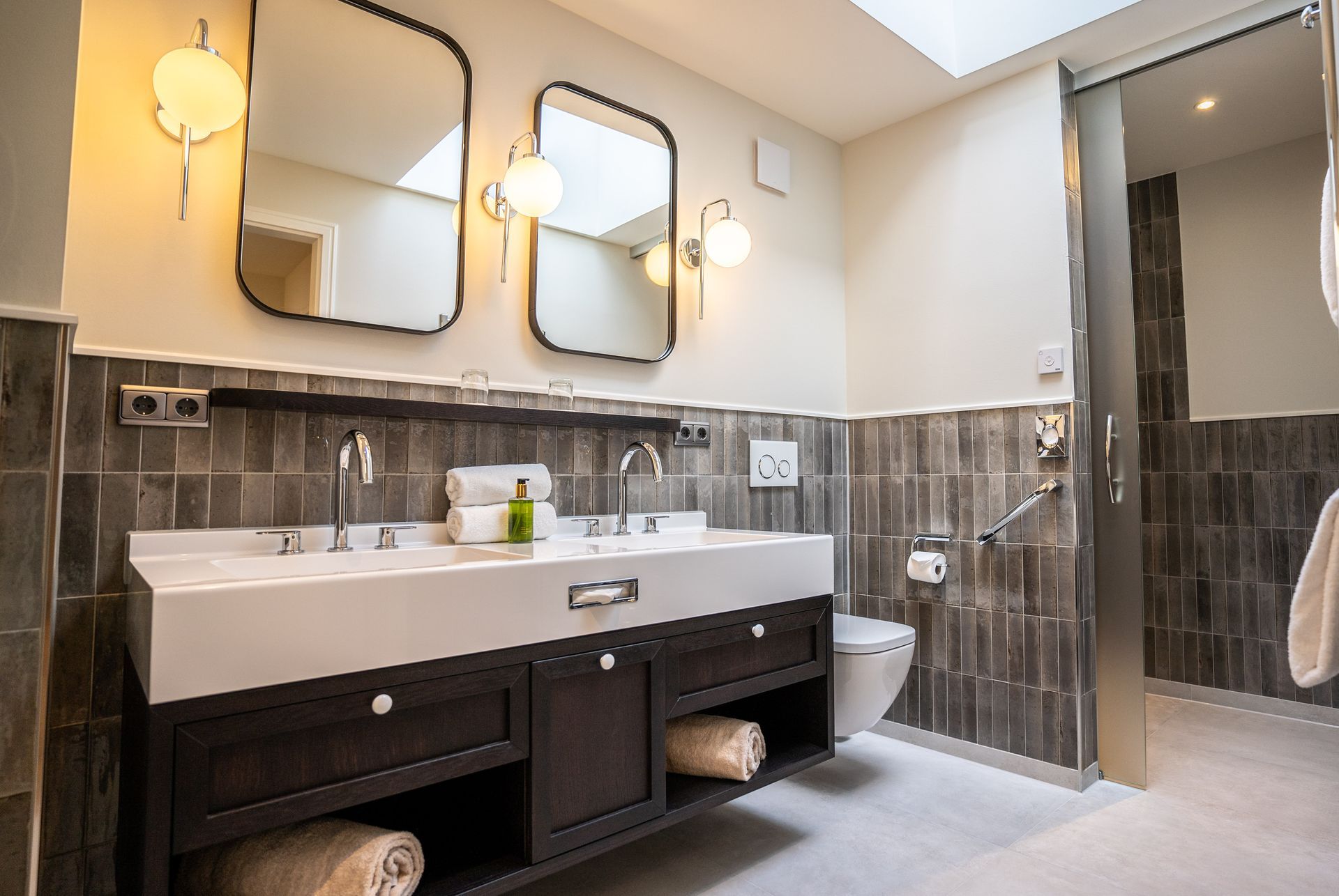 Ein Badezimmer mit zwei Waschbecken, zwei Spiegeln und einer Toilette.