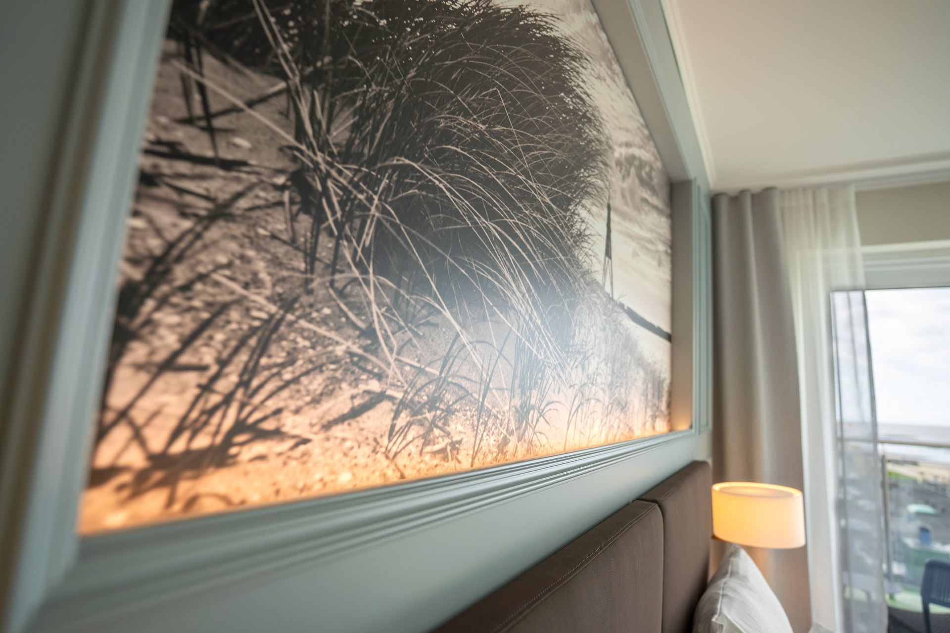 In einem Hotelzimmer hängt ein Gemälde an der Wand über dem Bett.