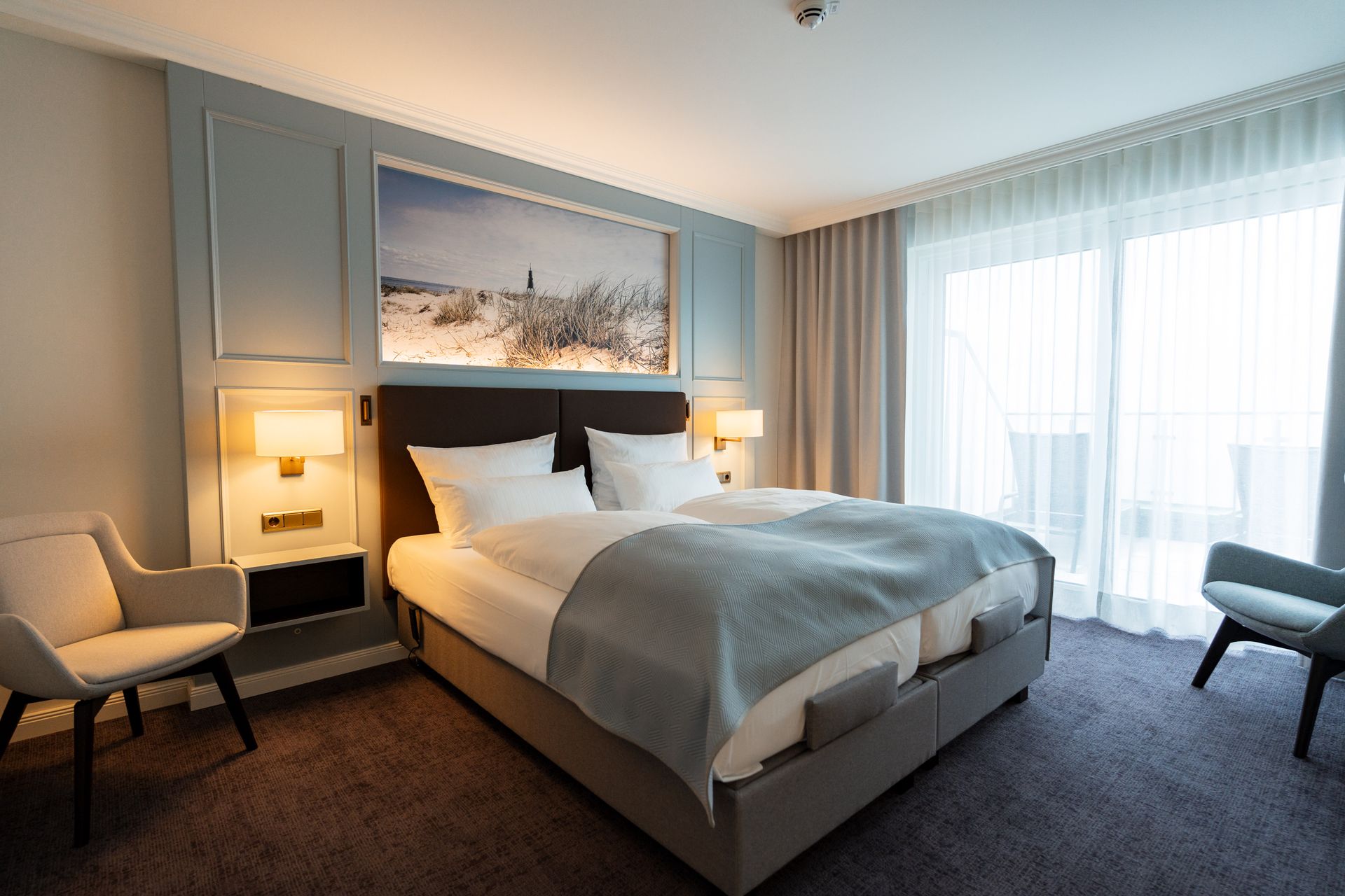 Ein Hotelzimmer mit großem Bett, Stühlen und Balkon.