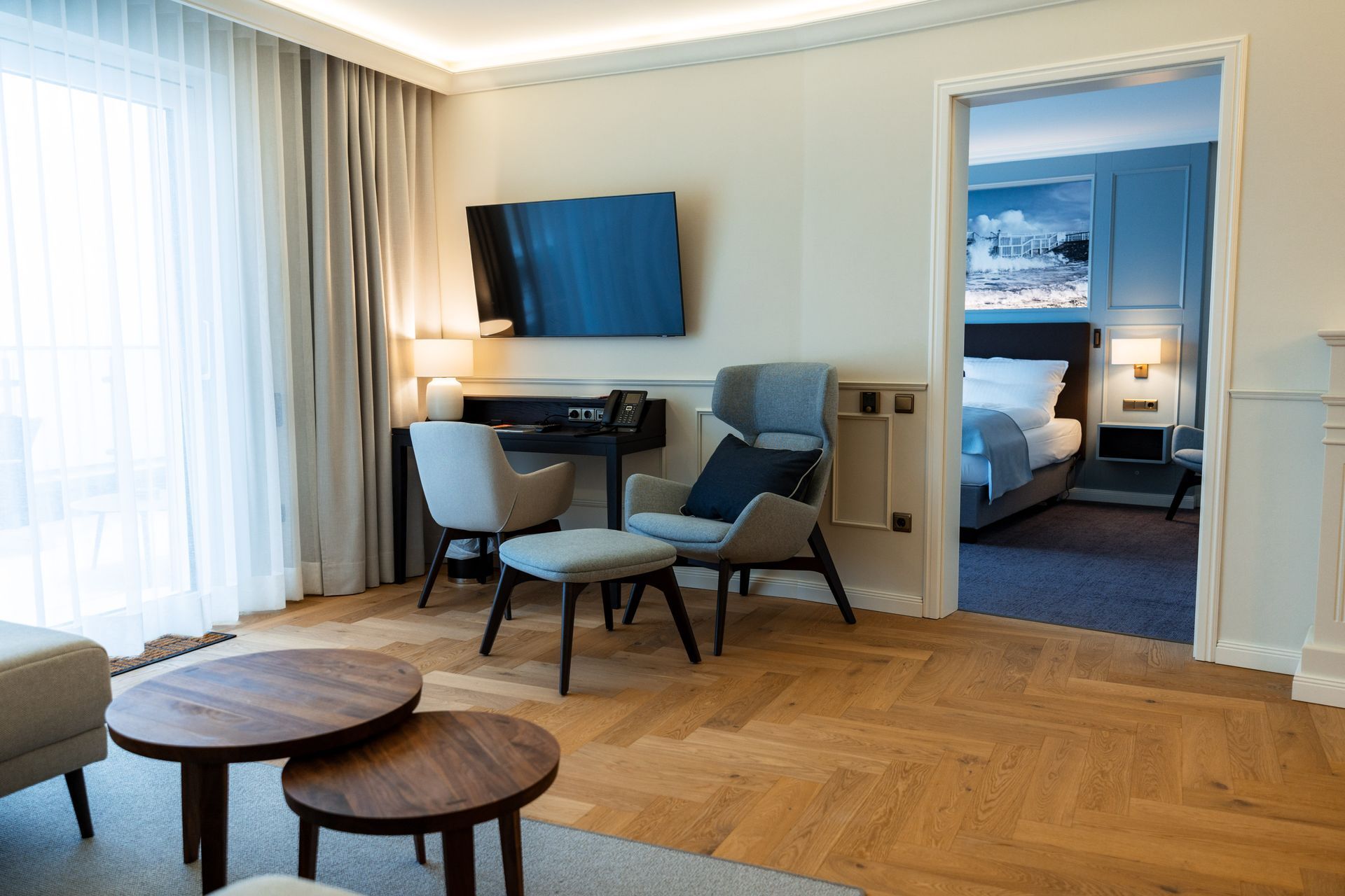 Ein Wohnzimmer mit Stühlen, Tischen und einem Flachbildfernseher.