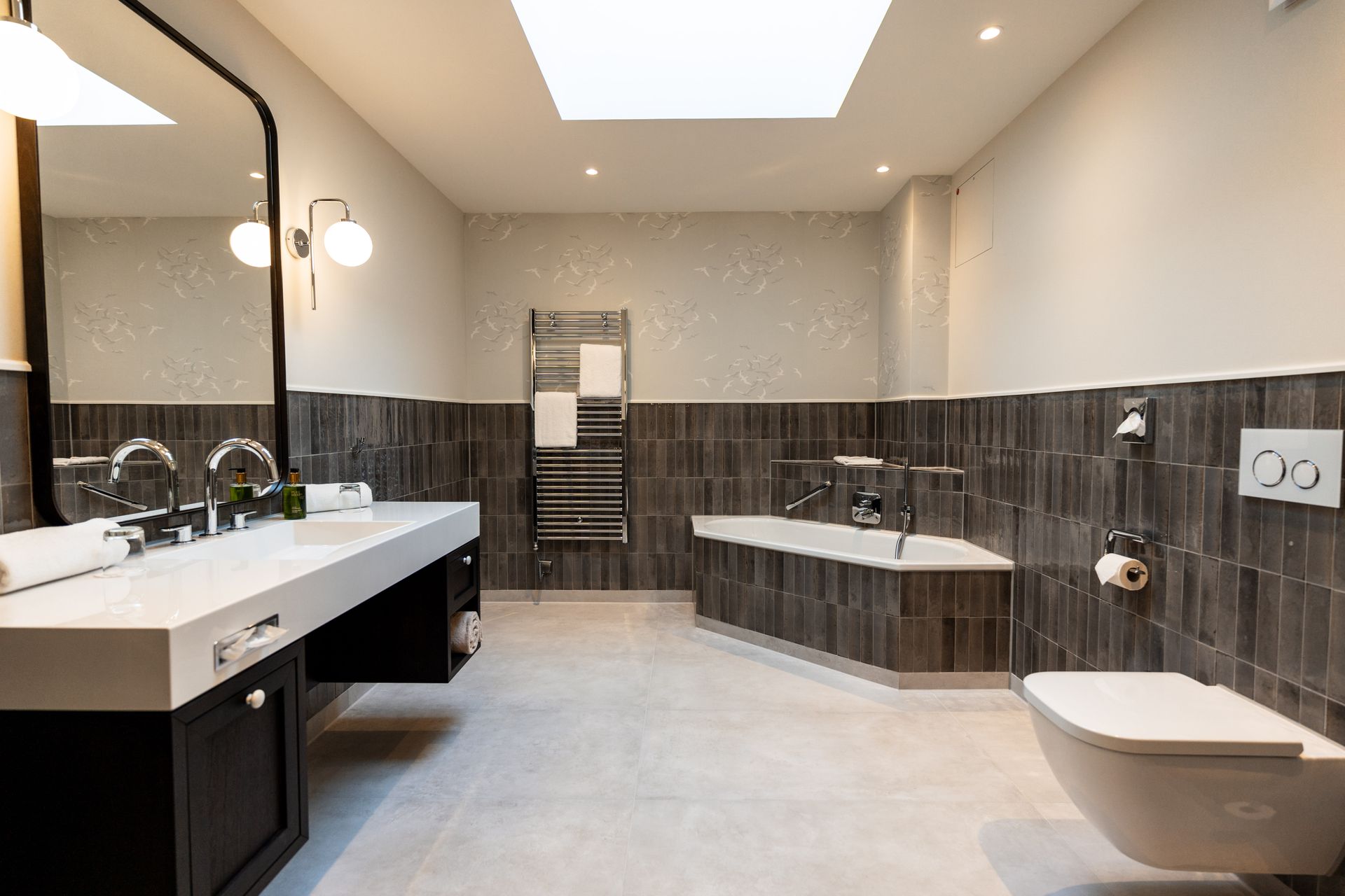 Ein Badezimmer mit Badewanne, Toilette, Waschbecken und Spiegel.