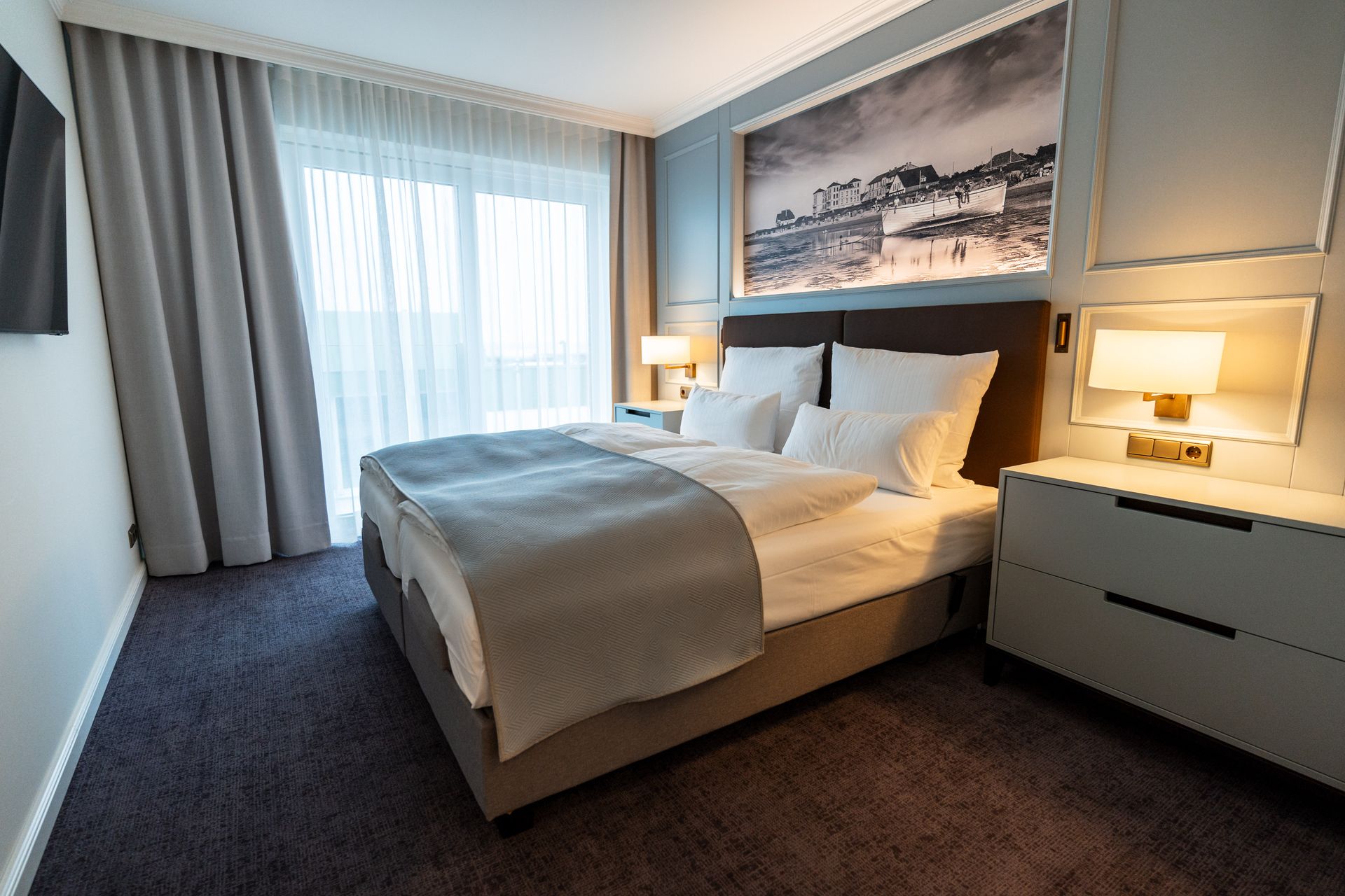 Ein Hotelzimmer mit Kingsize-Bett, Nachttisch, Fernseher und Balkon.