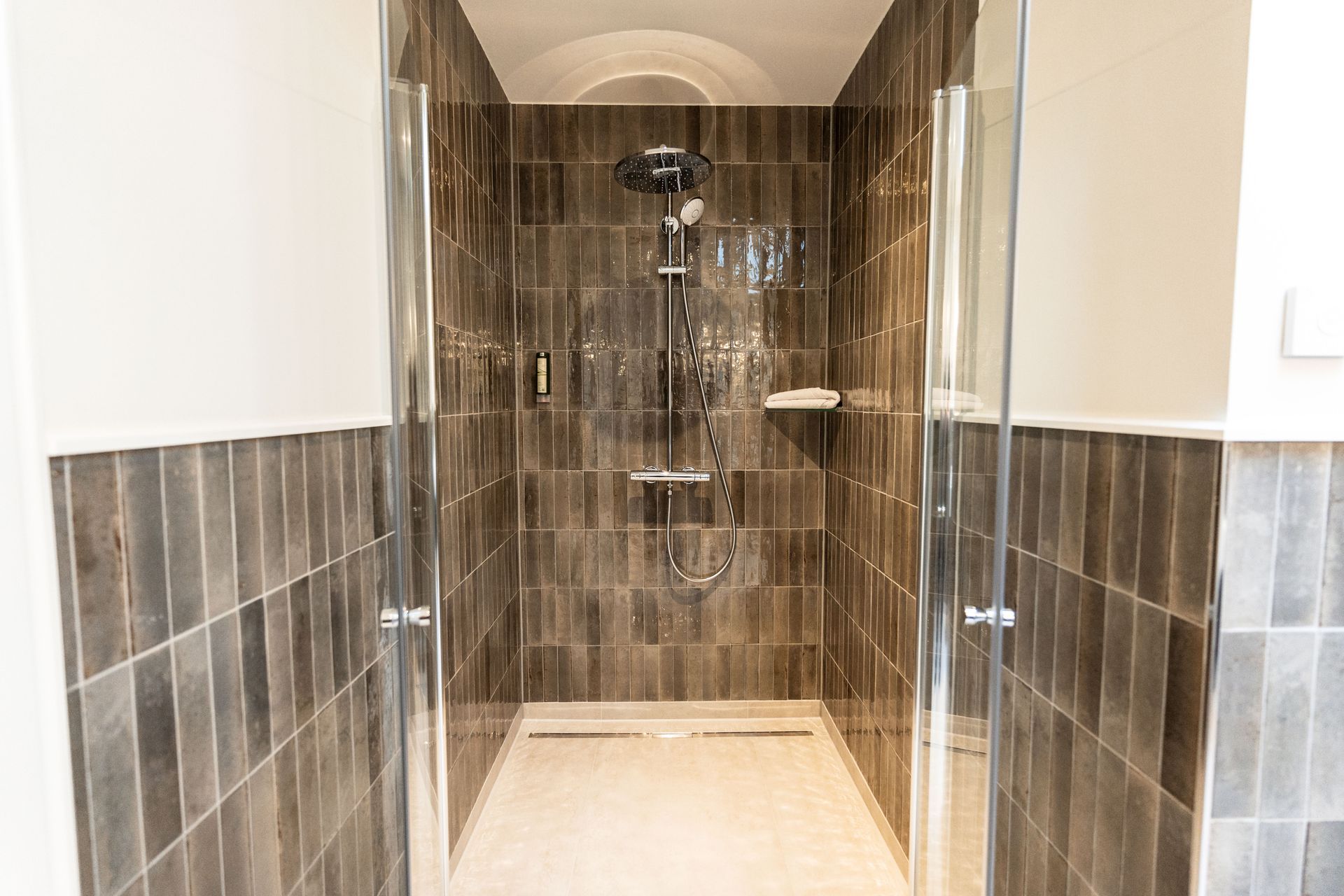 Ein Badezimmer mit ebenerdiger Dusche und Glastür.