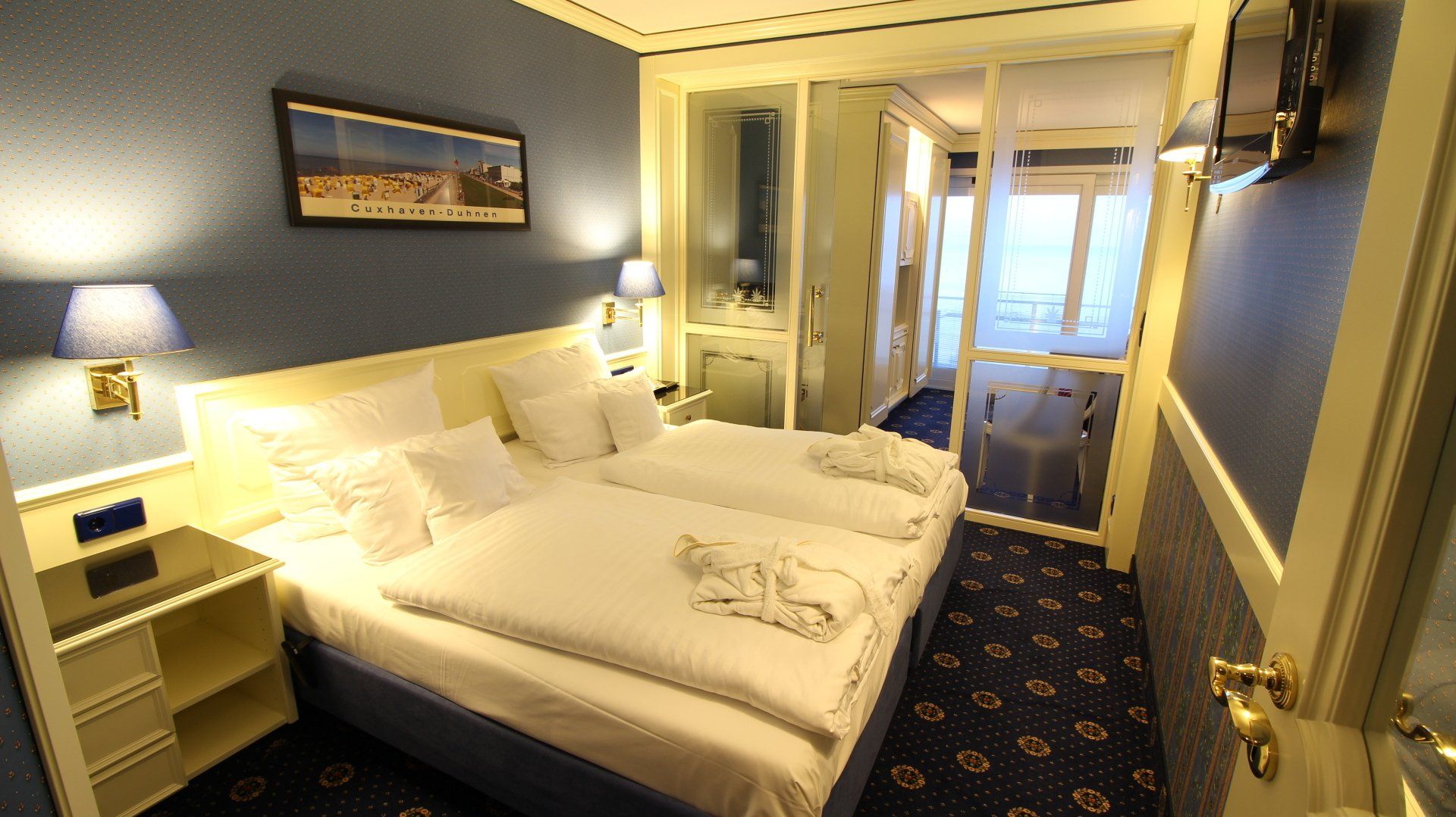 A hotel room with two beds and a picture on the wall