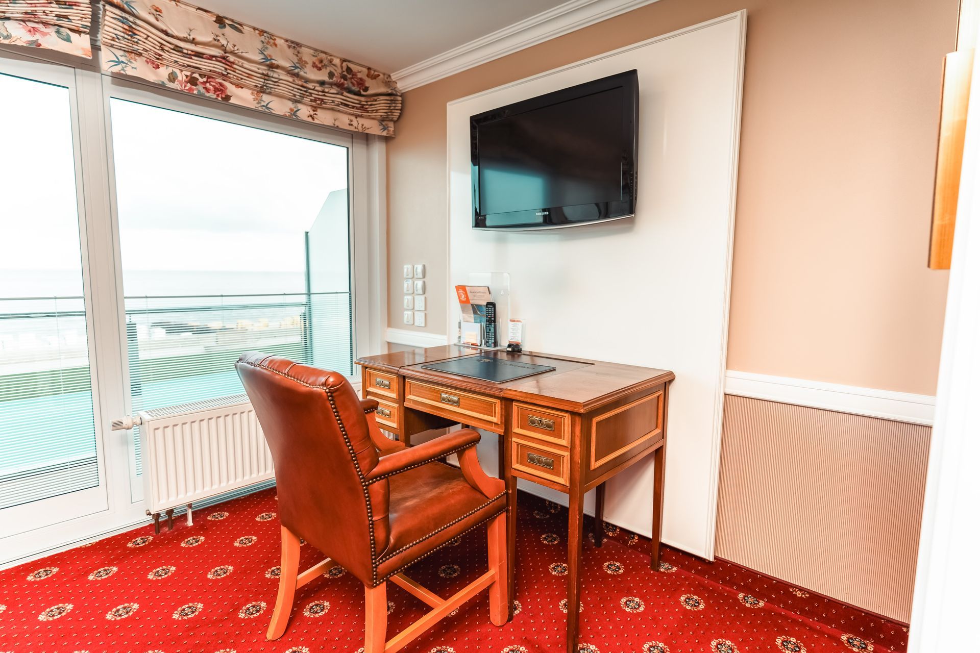 Ein Hotelzimmer mit Schreibtisch, Stuhl und Fernseher.