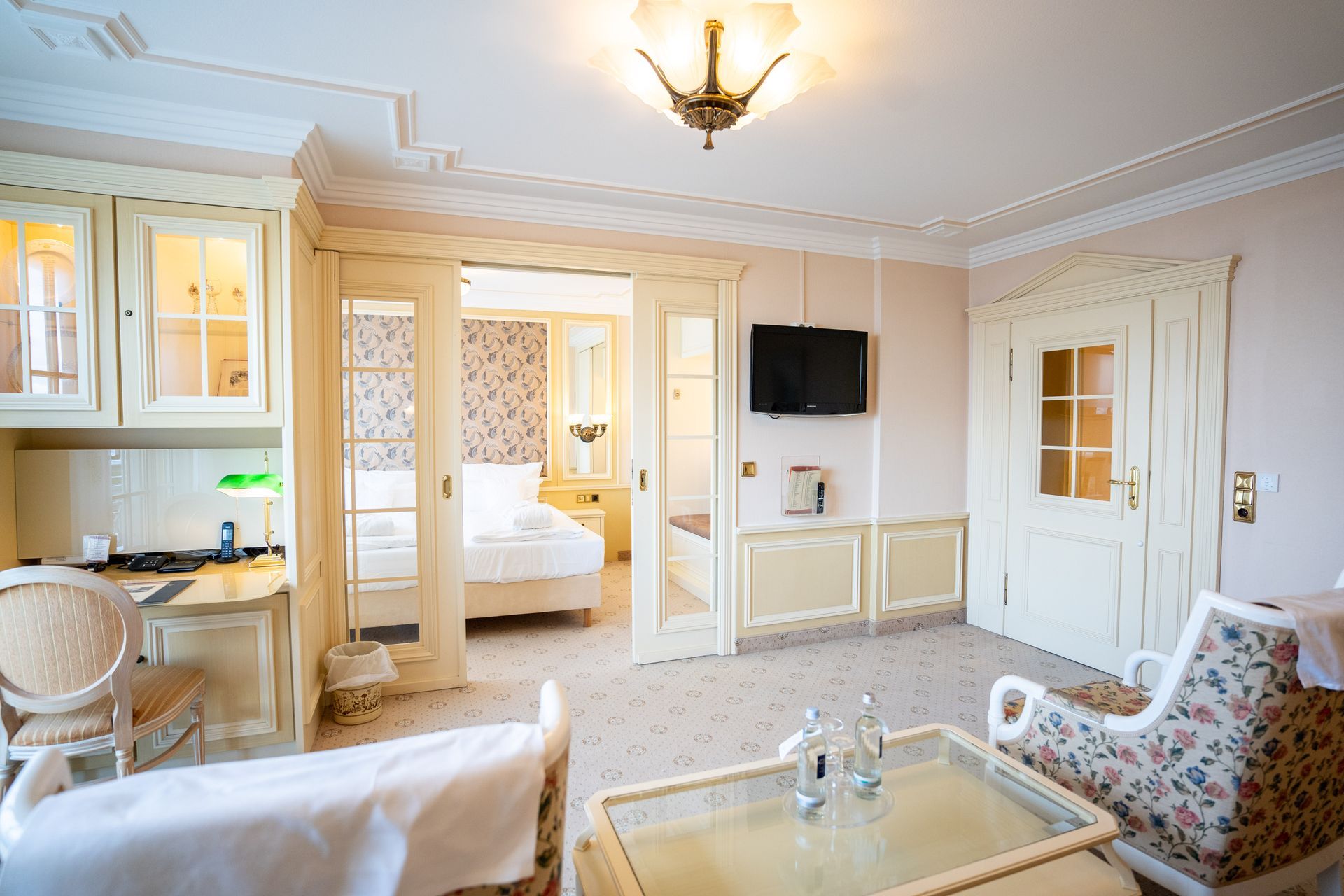 Ein Wohnzimmer mit einem Bett, Stühlen, einem Tisch und einem Fernseher.