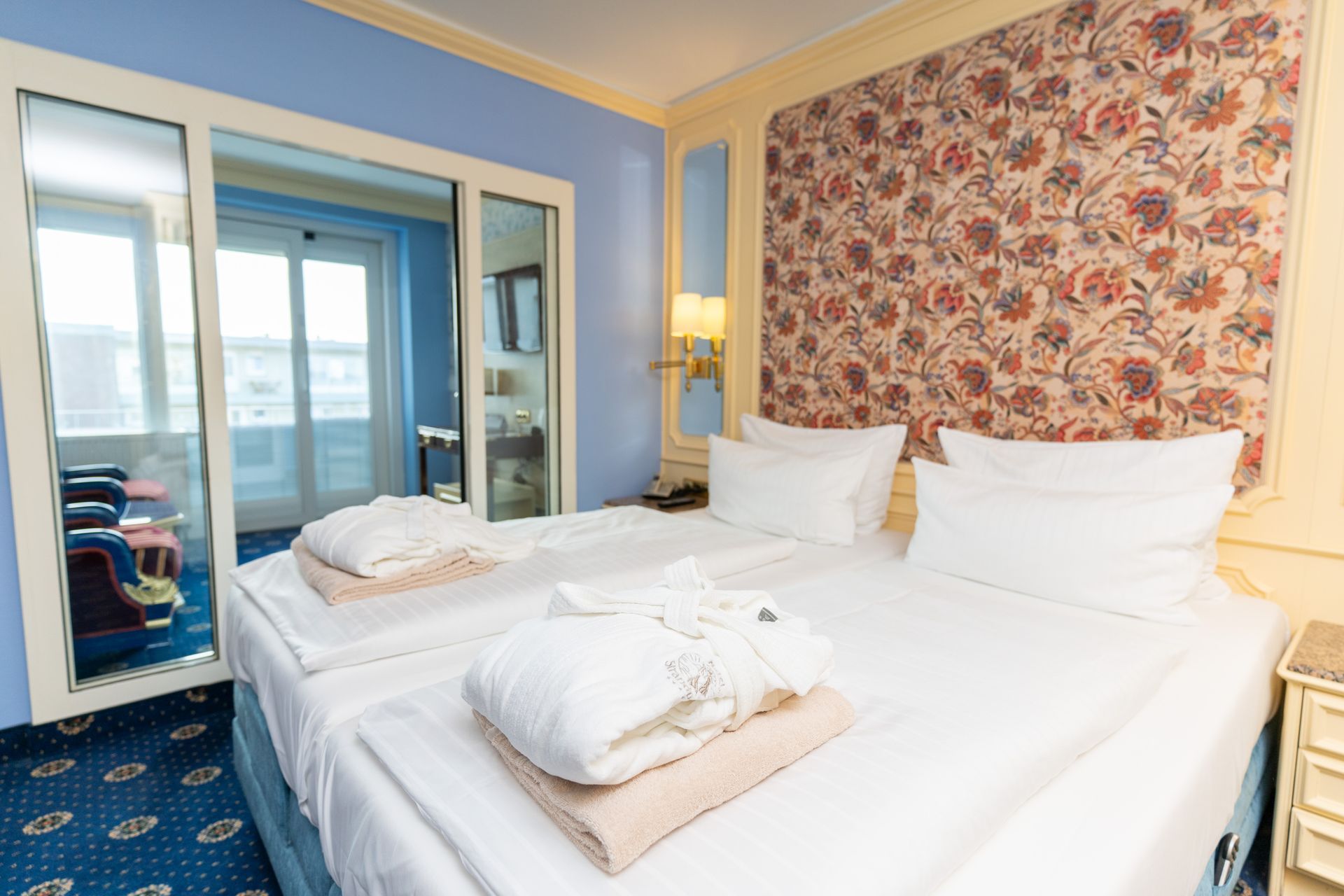 Ein Hotelzimmer mit zwei Betten und einer Glasschiebetür.