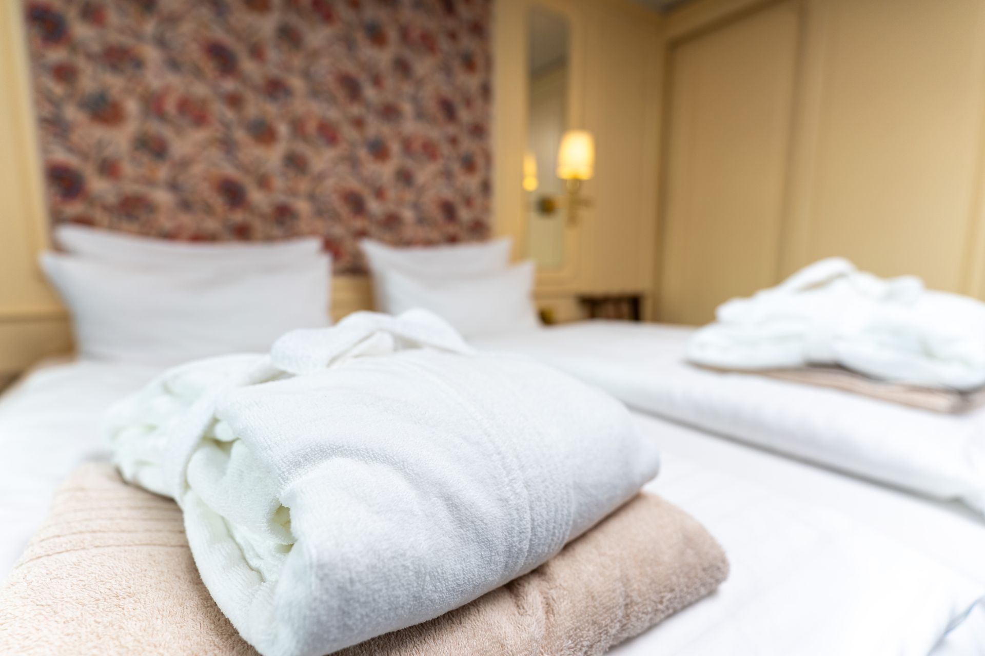 Auf einem Bett in einem Hotelzimmer liegen übereinander gestapelte Handtücher.