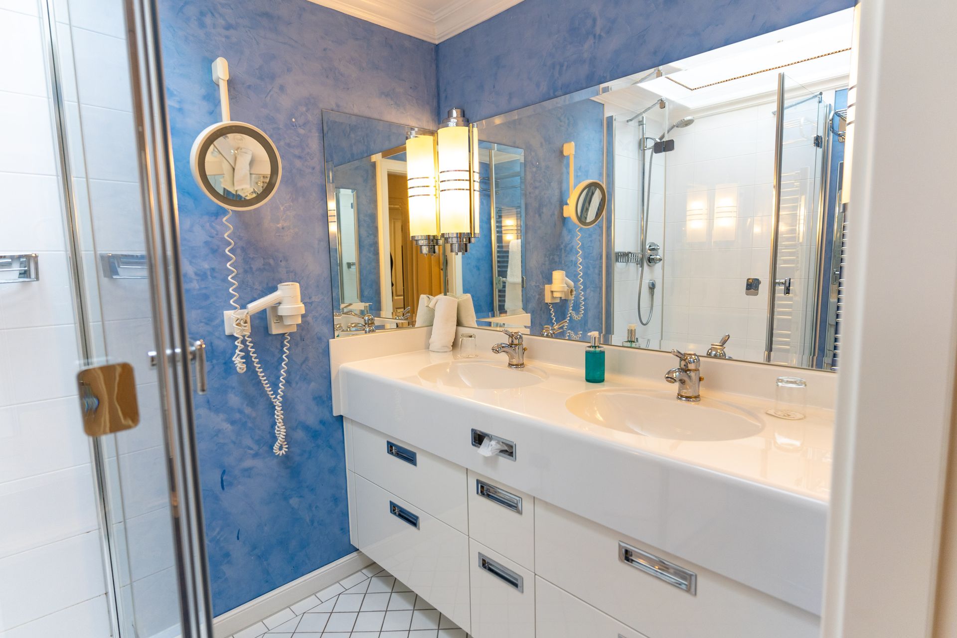 Ein Badezimmer mit zwei Waschbecken, einer Dusche und einem Spiegel.