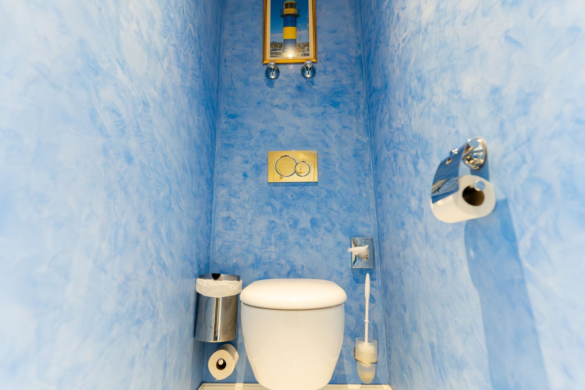 Ein kleines Badezimmer mit blauen Wänden und einer Toilette.