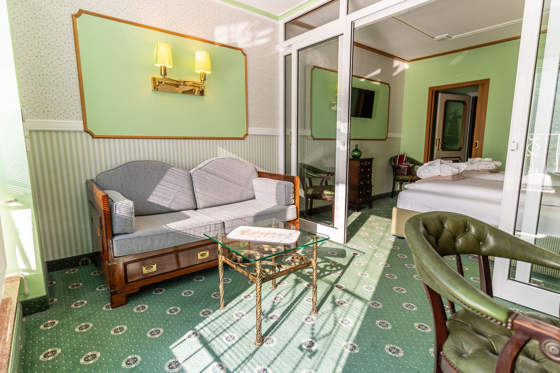 Ein Hotelzimmer mit Couch, Sessel, Tisch und Bett.