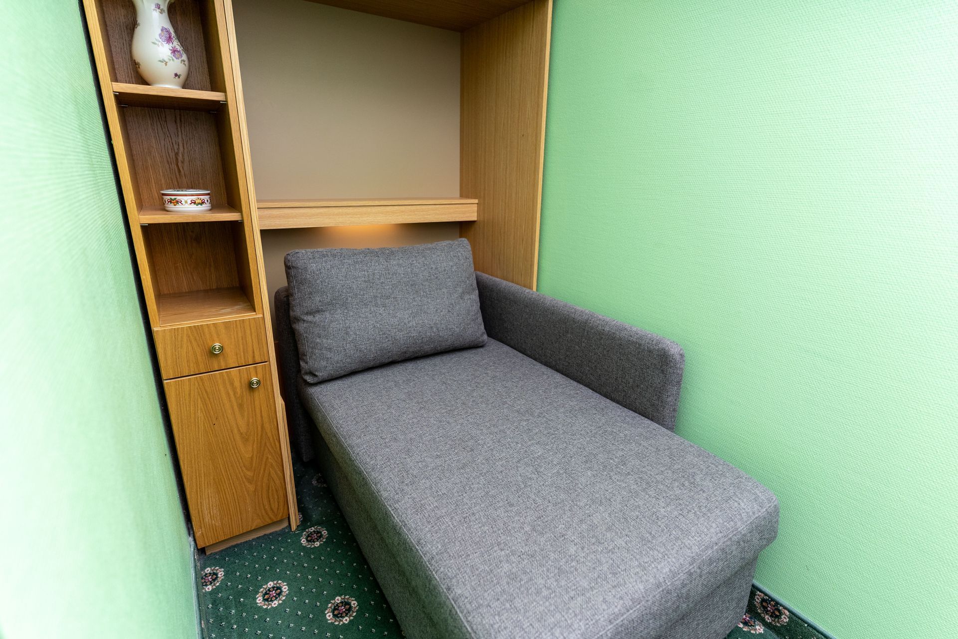 Ein kleines Zimmer mit einer Couch und einem Bücherregal.