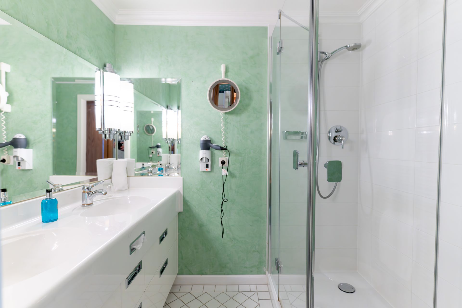 Ein Badezimmer mit zwei Waschbecken, einer Dusche und einem Spiegel.