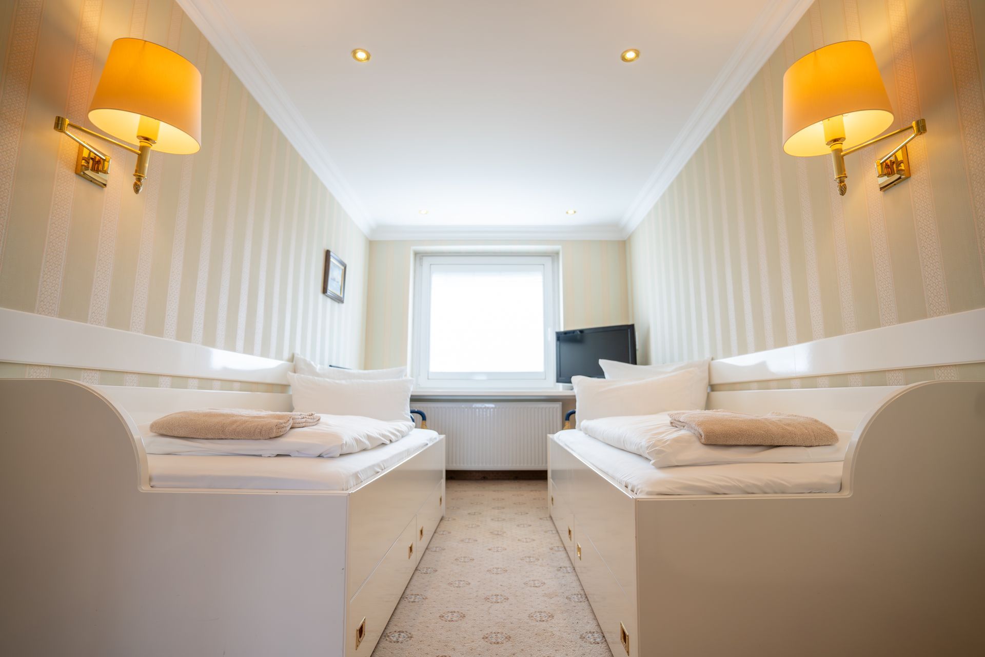 Ein Hotelzimmer mit zwei Betten und einem Fernseher.