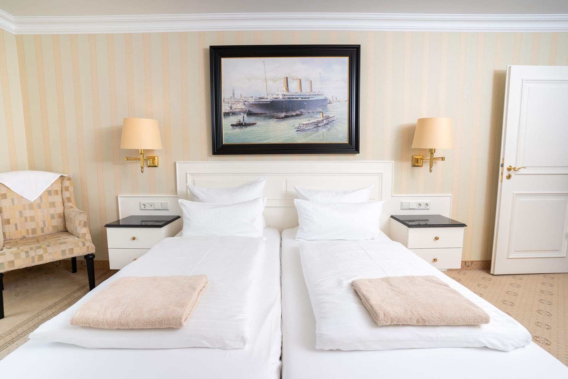 Ein Hotelzimmer mit zwei Betten und einem Gemälde an der Wand.
