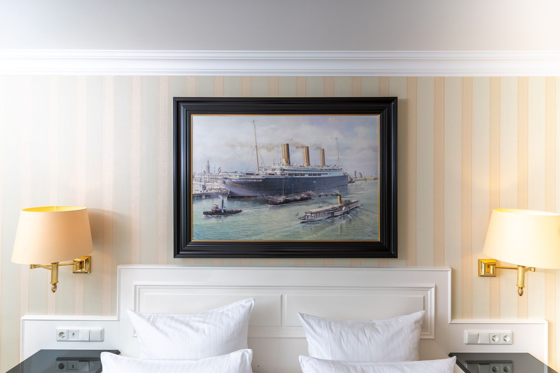 An der Wand über dem Bett hängt ein Gemälde eines Schiffes.