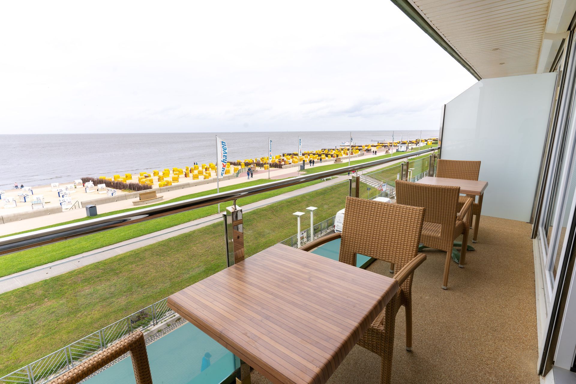 Ein Balkon mit Tischen und Stühlen mit Blick auf das Meer
