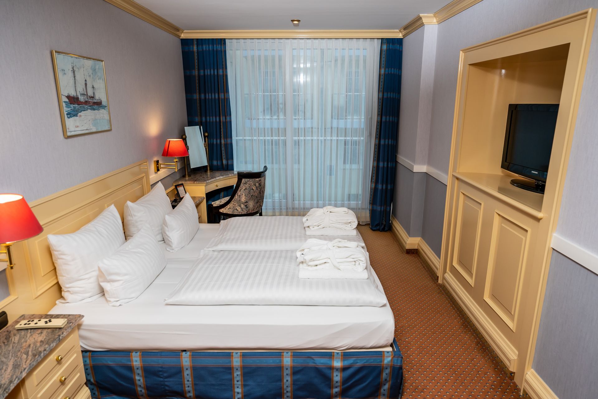 Ein Hotelzimmer mit zwei Betten, einem Schreibtisch und einem Fernseher.