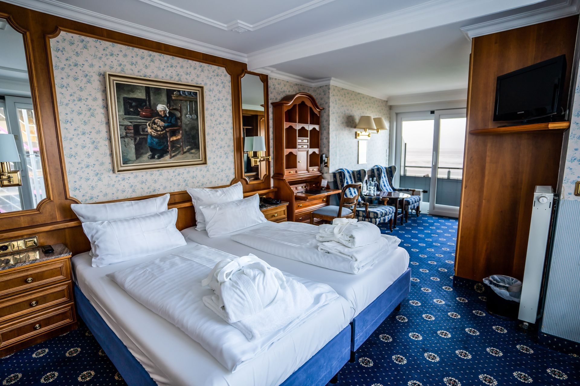 Ein Hotelzimmer mit zwei Betten und einem Gemälde an der Wand.