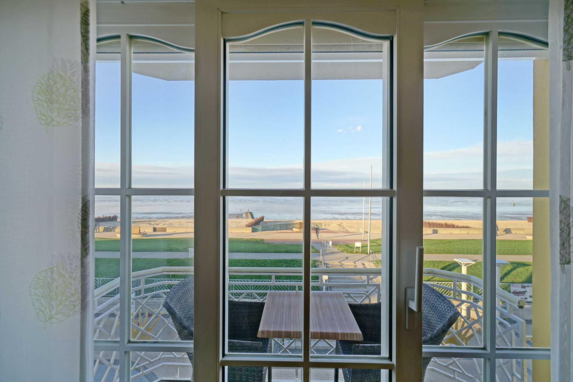 Ein Blick auf das Meer von einem Balkon mit Tisch und Stühlen.