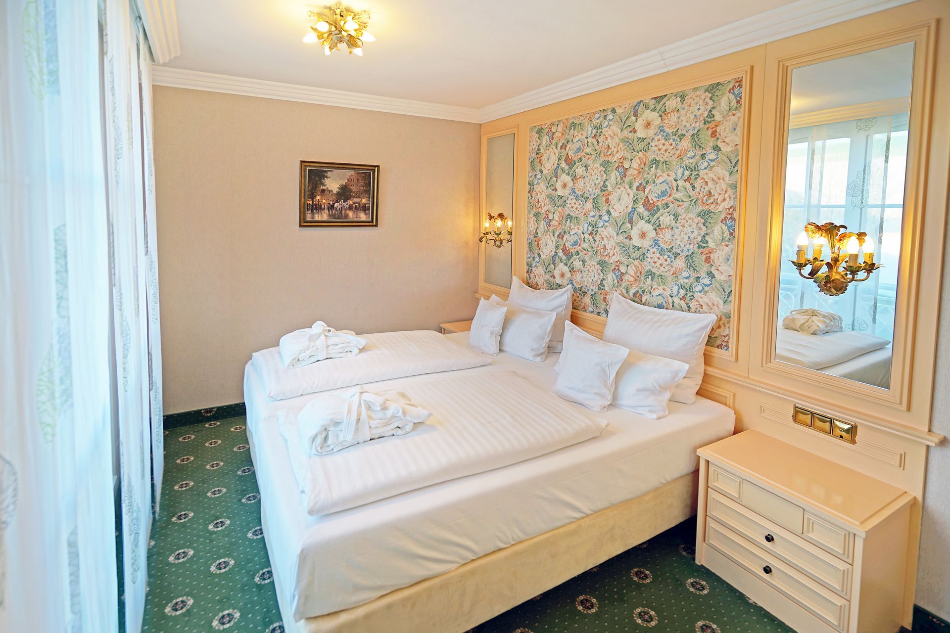 Ein Hotelzimmer mit Bett, Nachttisch, Spiegel und Fenster.