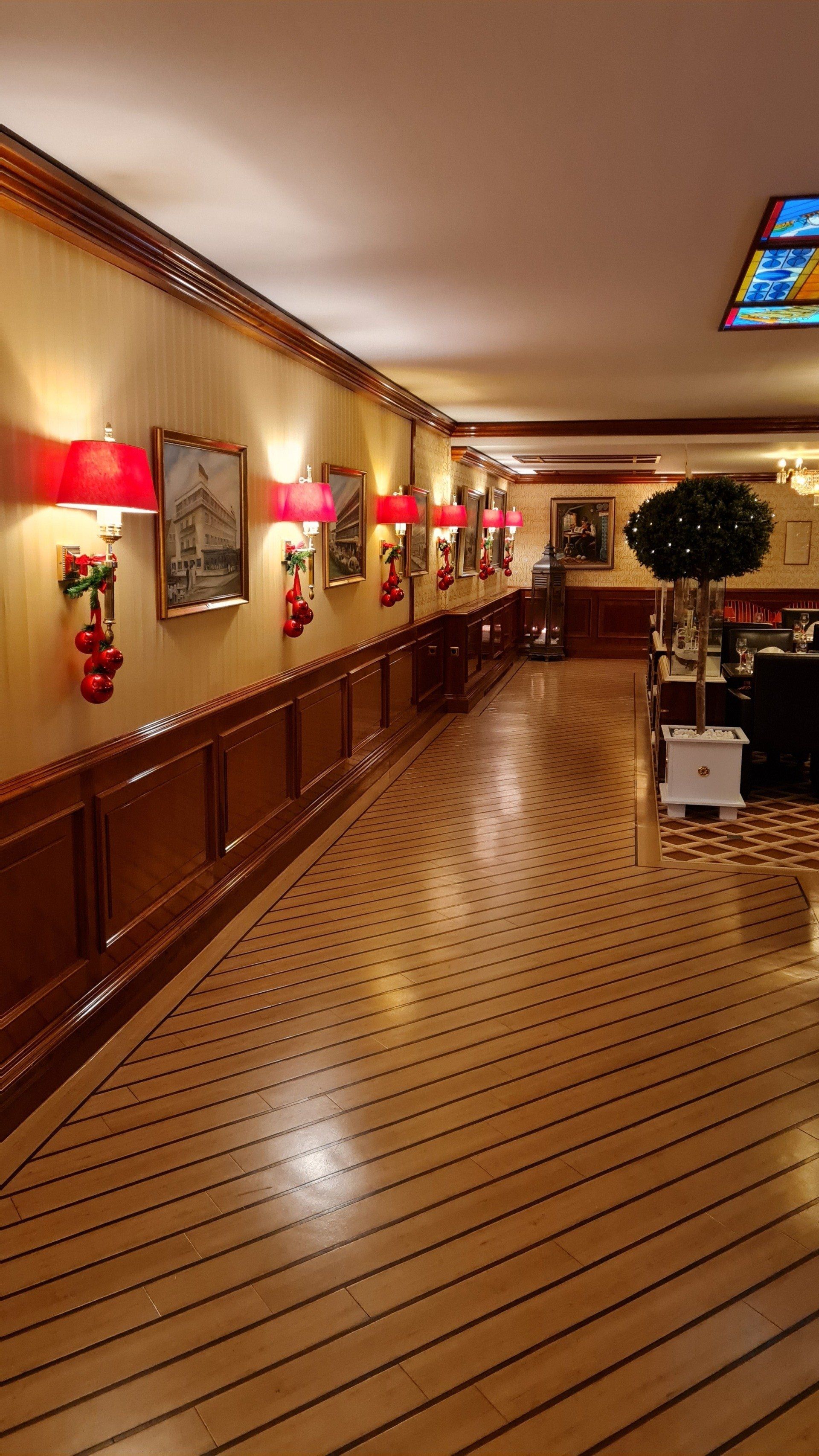 A long hallway with a wooden floor and a stained glass window.