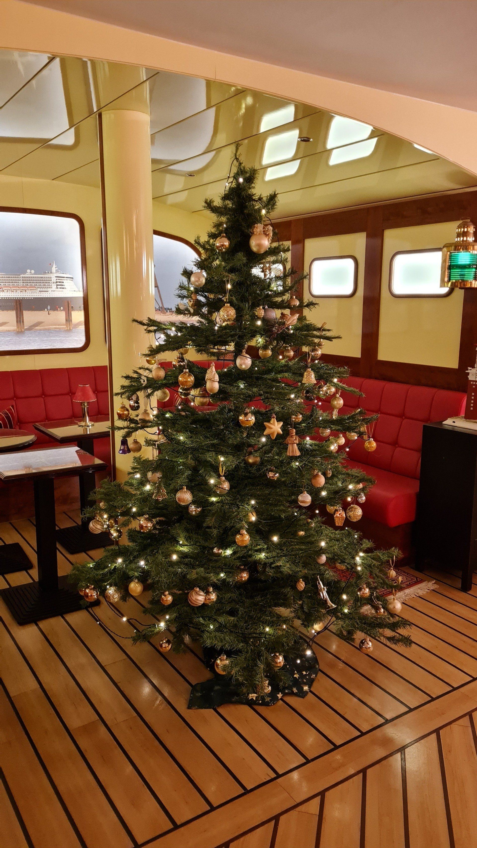 A christmas tree is sitting on a wooden floor in a room.