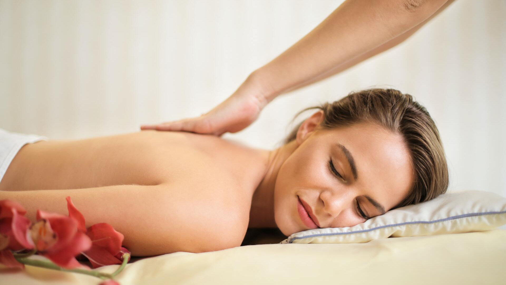 A woman is laying on a bed getting a massage from a man.