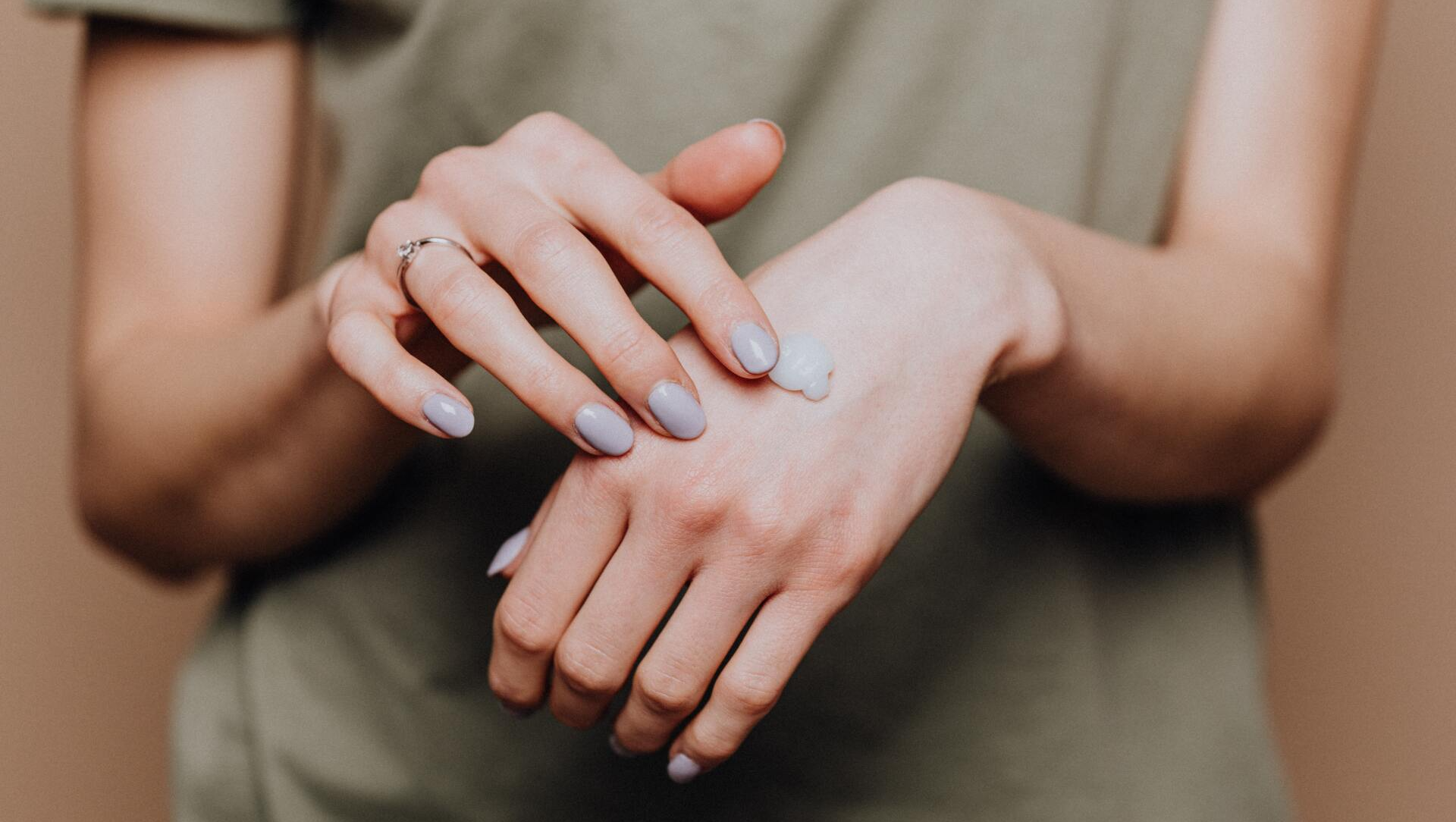 A woman is applying lotion to her hands.