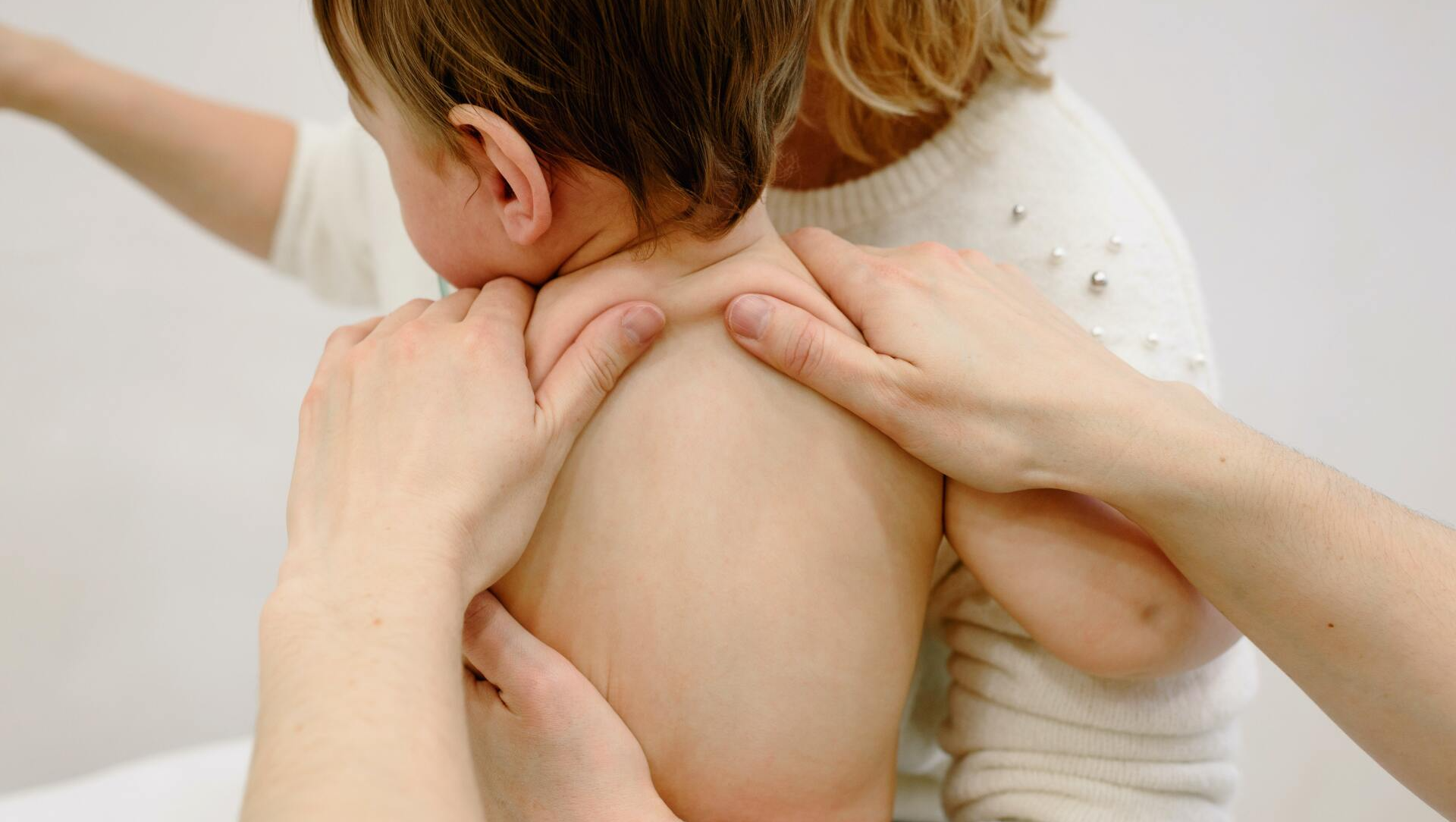 A woman is giving a baby a massage on his back.